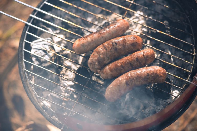 Close-up top view of grilling sausages on barbecue grill outdoors